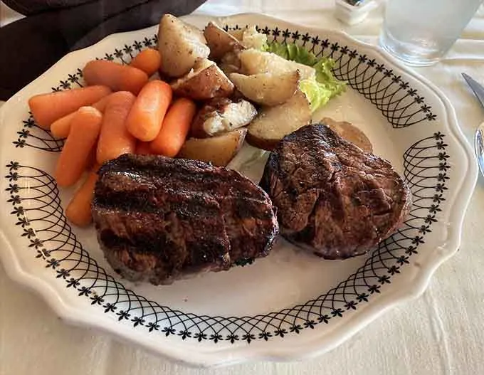 Two filets mignons with carrots and potatoes on decorated china
